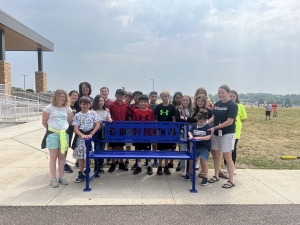A Buddy Bench has been created to be placed on the Prairie Ridge Intermediate School playground. Debbie Schell, former fourth grade teacher at Prairie Ridge, back left, is seen here with her former students, who all made the bench a reality. (Submitted photo)