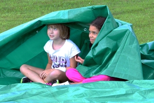 Kids wrap up in a tarp to protect against the cool wind that was blowing late last Monday afternoon. They had evacuated from Prairie Ridge Intermediate during a staged drill.